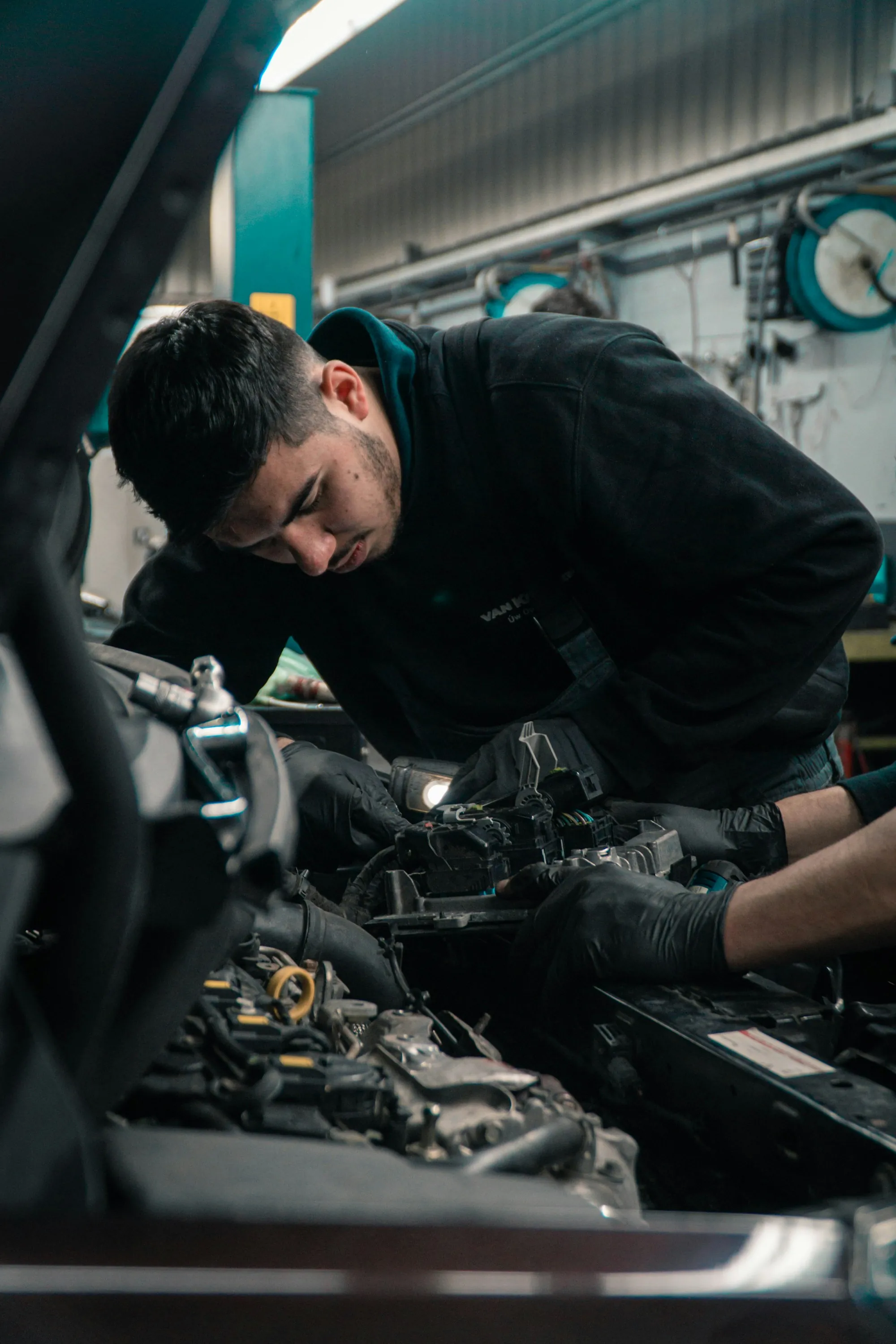 Mechanic leaning into an engine bay under shop lights