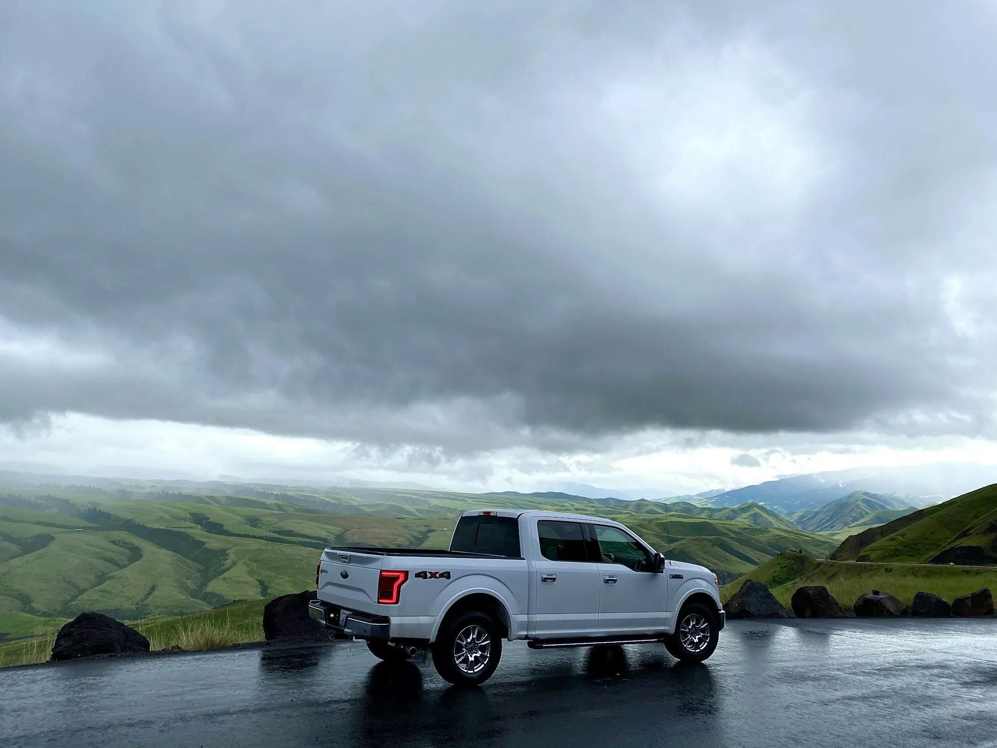 White pickup parked on a grassy ridge under a stormy sky