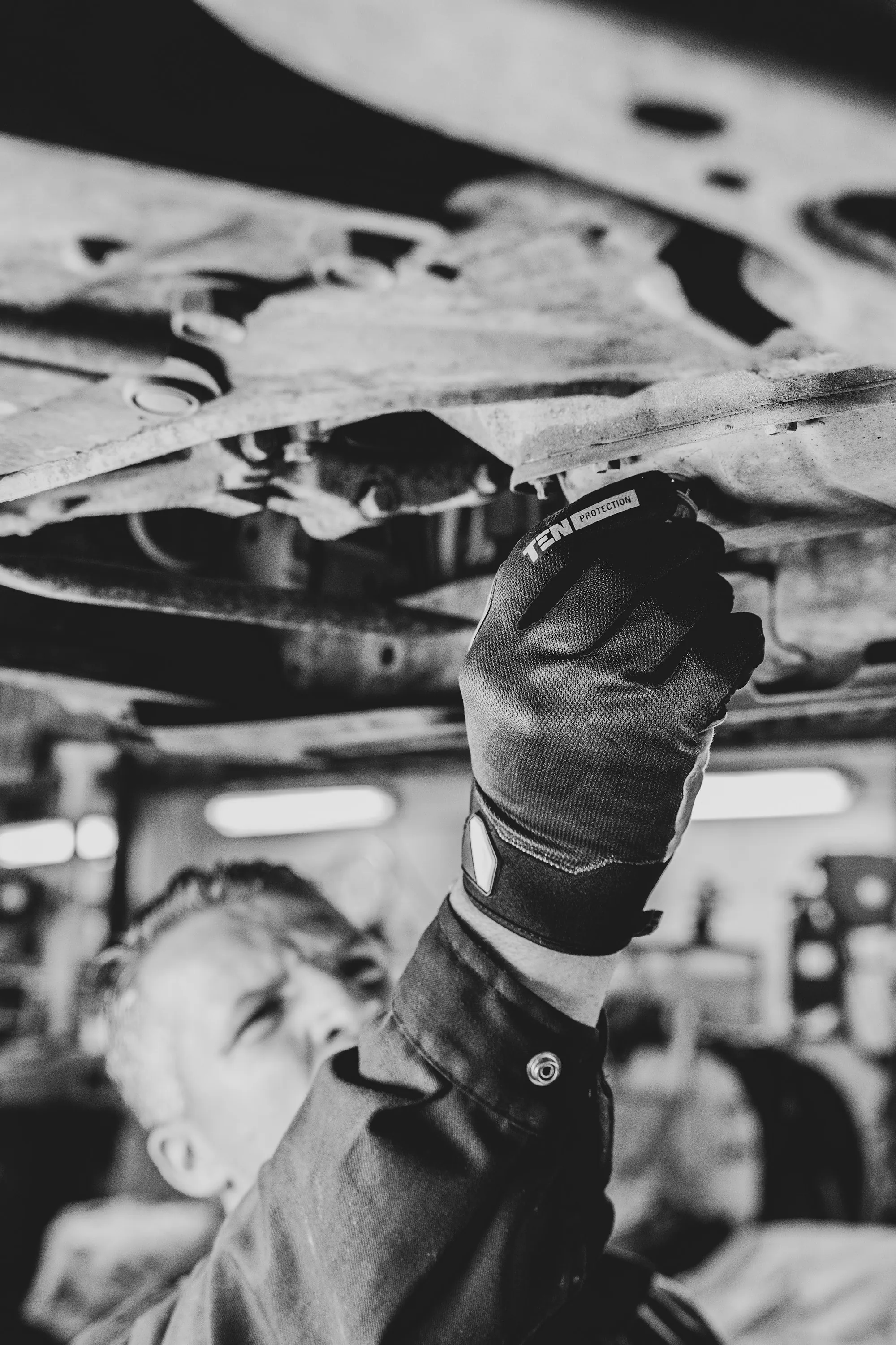 Mechanic underneath a vehicle on a lift checking components